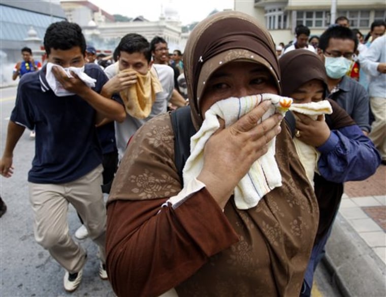 Malaysian activists cover themselves with towels as they run away from tear gas fired by police during a rally calling for electoral reforms in Kuala Lumpur on Saturday.